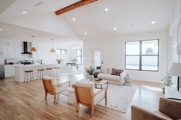 Bright open-plan living room with vaulted ceiling, exposed beam, and full kitchen