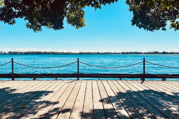Sunny wooden dock with rope railing overlooking a calm blue lake
